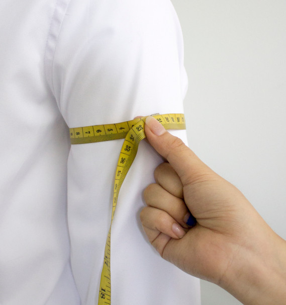 A person measuring the sleeve of a shirtDescription automatically generated