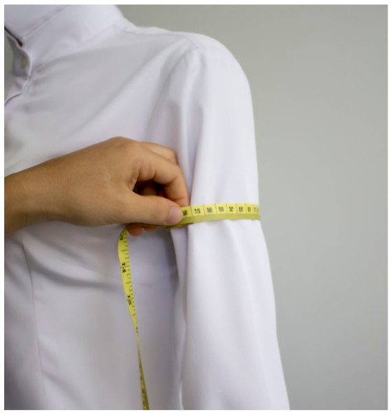 A person measuring the sleeve of a shirtDescription automatically generated