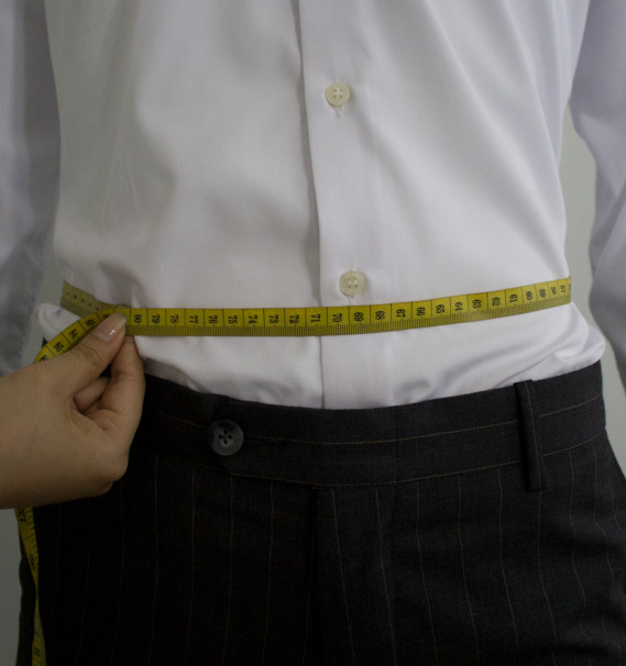 A person measuring a waistlineDescription automatically generated