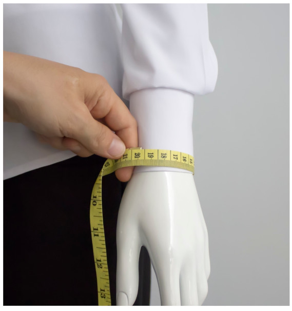 A person measuring a mannequin's wristDescription automatically generated