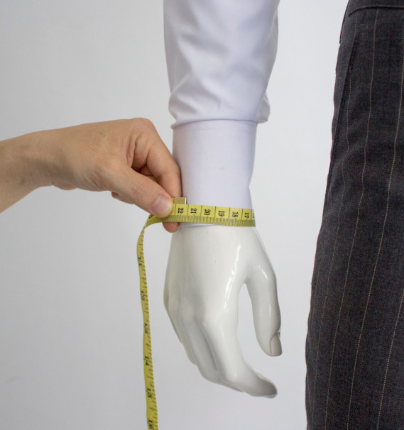 A person measuring a mannequin's wristDescription automatically generated