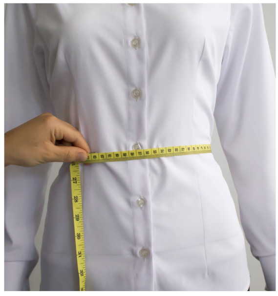 A person measuring her waistDescription automatically generated