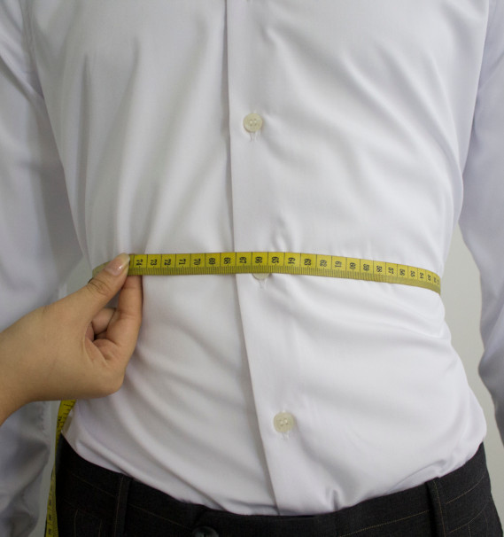 A person measuring her waistDescription automatically generated