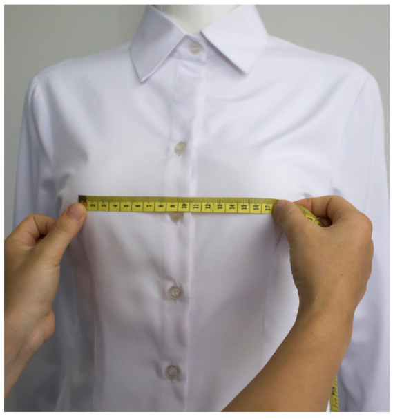 A close-up of a mannequin measuring a shirtDescription automatically generated