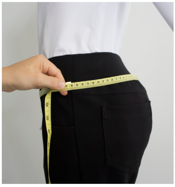 A person measuring her waistDescription automatically generated