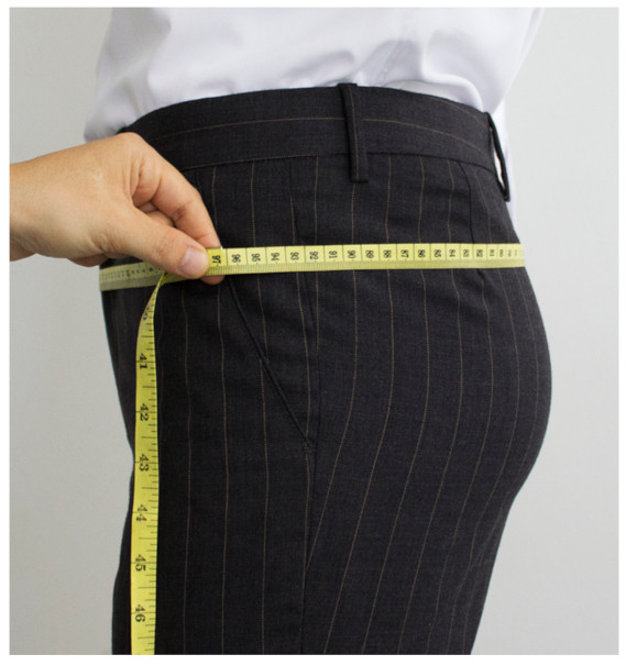 A person measuring her waistDescription automatically generated