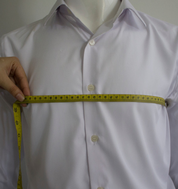 A hand measuring a shirtDescription automatically generated