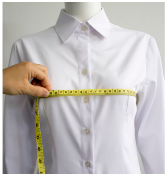 A hand measuring a shirtDescription automatically generated