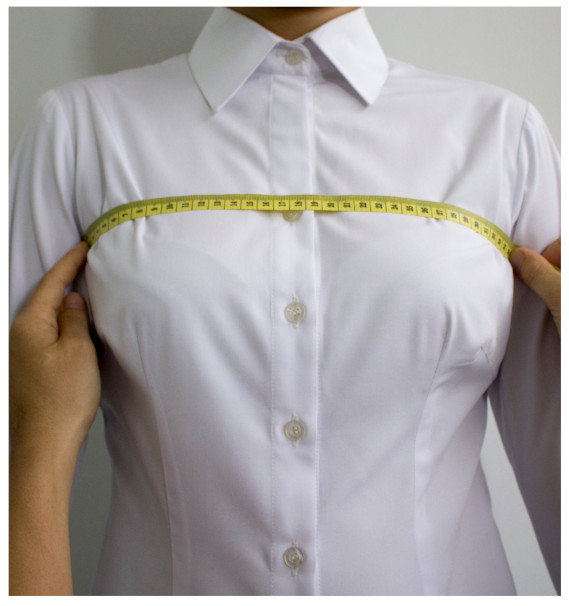 A person measuring her chest with a measuring tapeDescription automatically generated